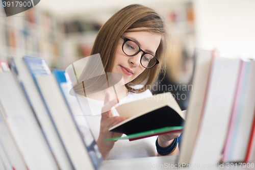 Image of portrait of famale student selecting book to read in library