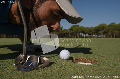 Image of golf player blowing ball in hole