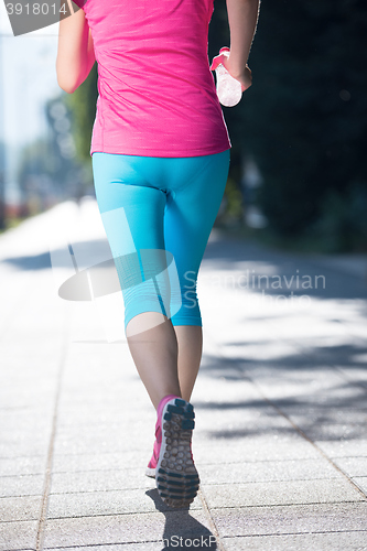 Image of sporty woman running  on sidewalk