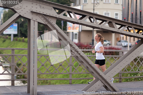 Image of sporty woman running  on sidewalk