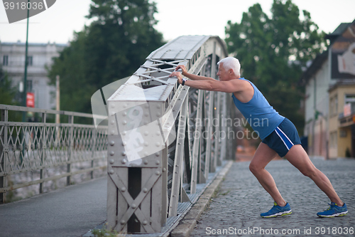 Image of handsome man stretching before jogging