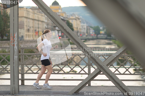 Image of sporty woman running  on sidewalk