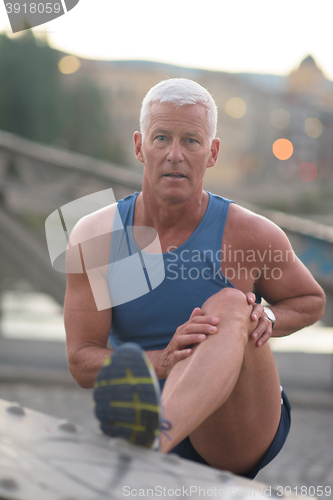 Image of handsome man stretching before jogging