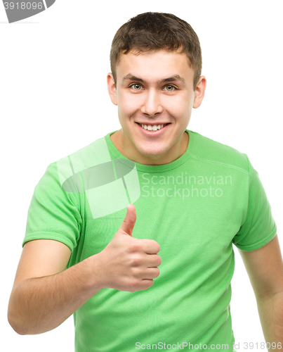 Image of Cheerful young man showing thumb up sign