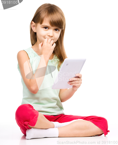 Image of Young girl is using tablet while sitting on floor