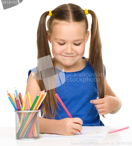 Image of Little girl is drawing using pencils