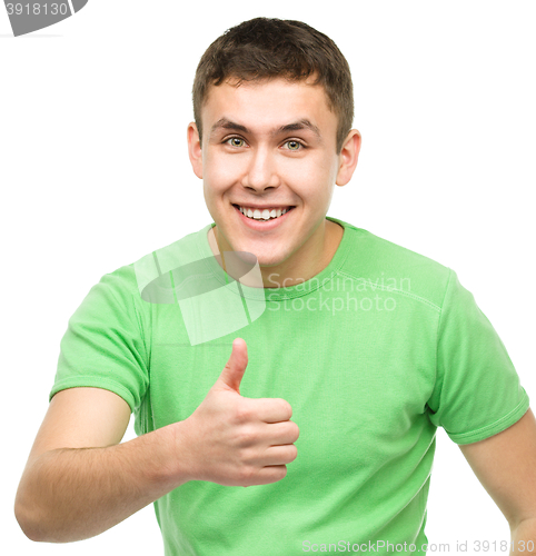 Image of Cheerful young man showing thumb up sign