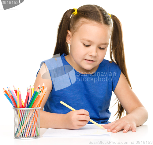 Image of Little girl is drawing using pencils