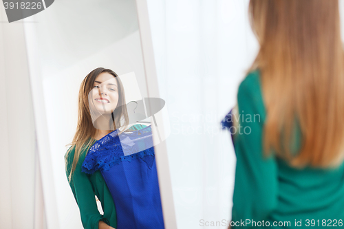 Image of happy woman choosing clothes at home wardrobe