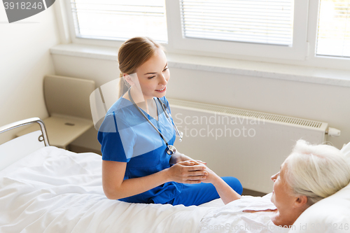 Image of doctor or nurse visiting senior woman at hospital