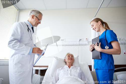 Image of doctor and nurse visiting senior woman at hospital