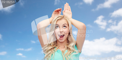 Image of happy smiling young woman making bunny ears