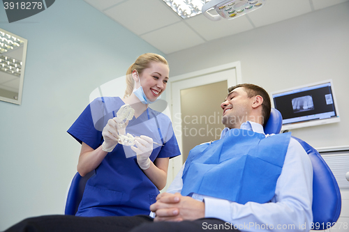 Image of happy dentist showing jaw layout to male patient