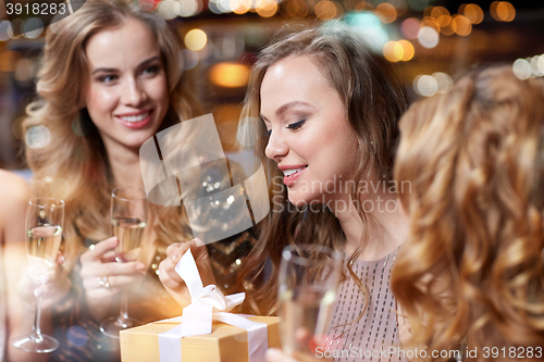 Image of happy women with champagne and gift at night club