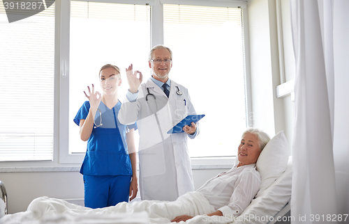 Image of doctor and nurse visiting senior woman at hospital