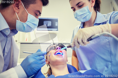 Image of dentists treating woman patient teeth at clinic