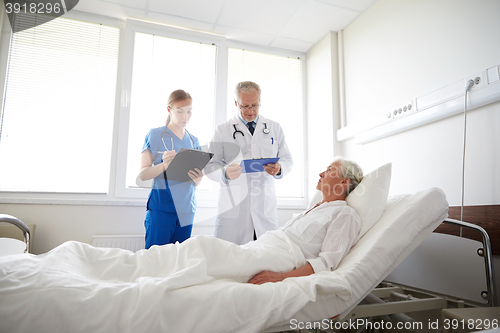 Image of doctor and nurse visiting senior woman at hospital