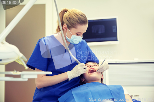 Image of female dentist checking patient girl teeth