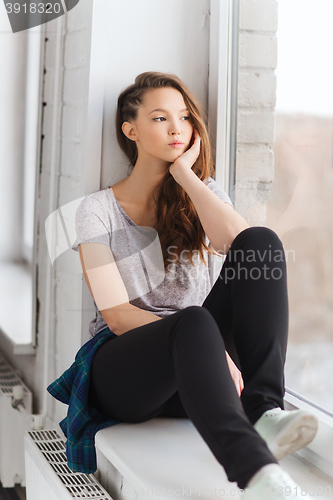 Image of sad pretty teenage girl sitting on windowsill