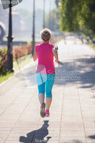 Image of sporty woman running  on sidewalk