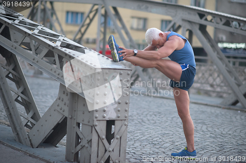 Image of handsome man stretching before jogging