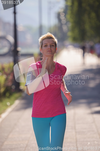 Image of sporty woman running  on sidewalk