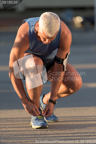 Image of Man tying running shoes laces