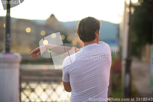 Image of handsome man stretching before jogging