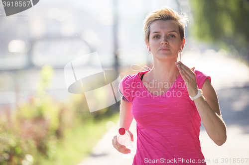 Image of sporty woman running  on sidewalk