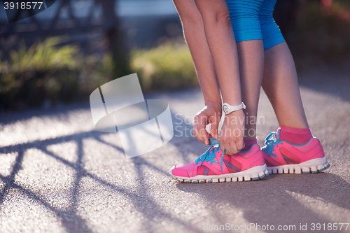 Image of Closeup of woman tying running shoe