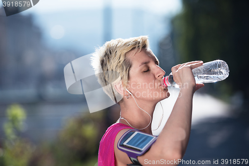 Image of woman drinking  water after  jogging