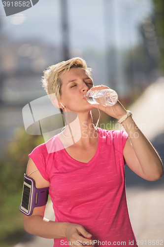 Image of woman drinking  water after  jogging