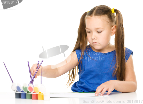 Image of Little girl is drawing using pencils