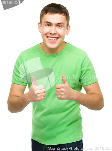 Image of Cheerful young man showing thumb up sign