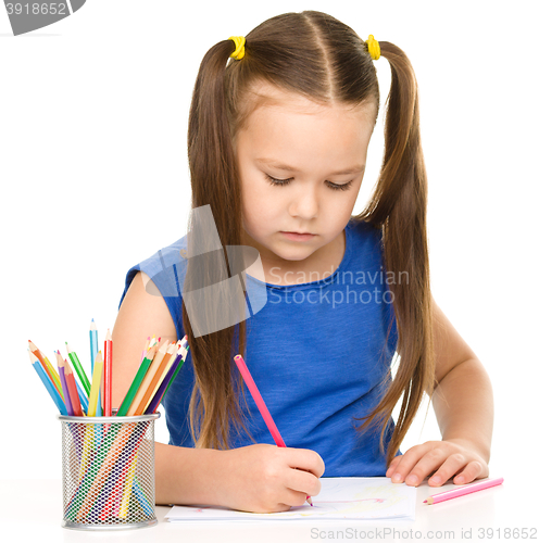 Image of Little girl is drawing using pencils