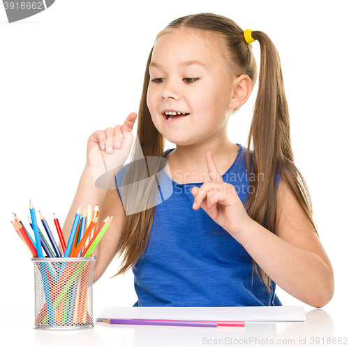 Image of Little girl is drawing using pencils