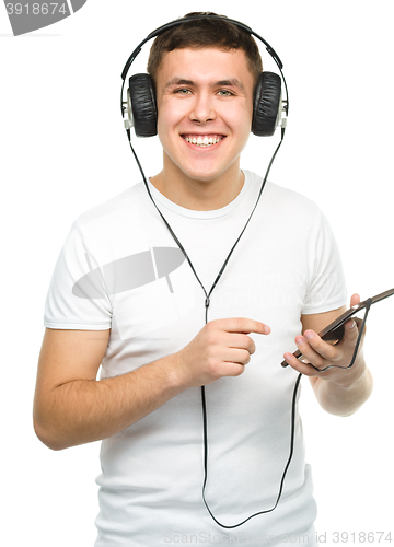 Image of Young man enjoying music using headphones