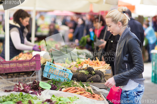 Image of Woman buying vegetable at local food market. 