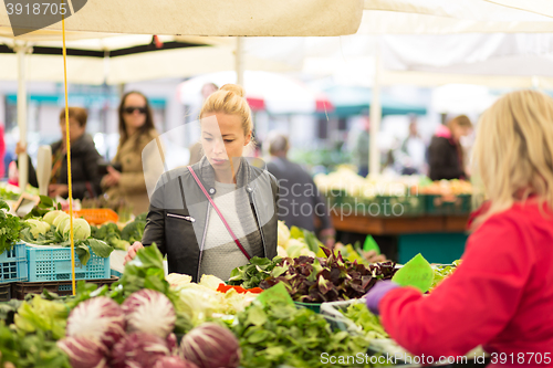 Image of Woman buying vegetable at local food market. 