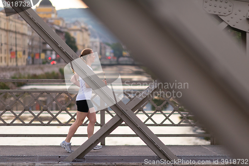 Image of sporty woman running  on sidewalk