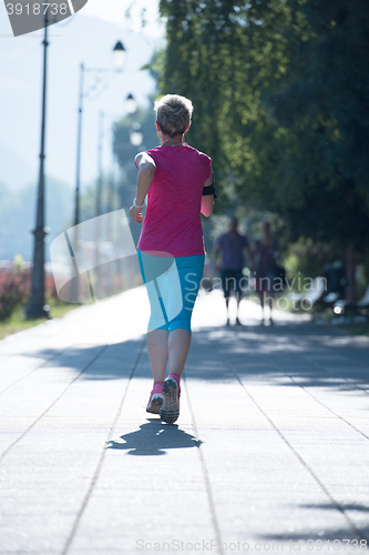 Image of sporty woman running  on sidewalk