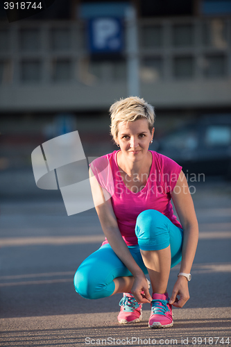 Image of Closeup of woman tying running shoe