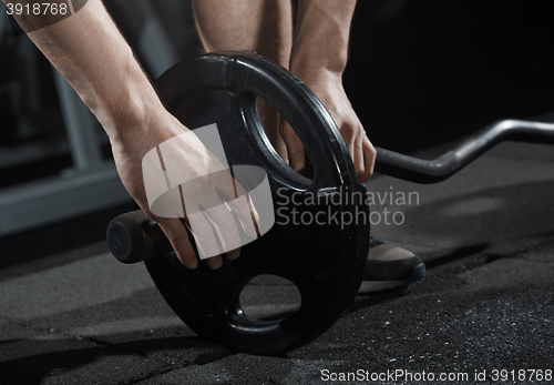 Image of Man preparing barbell at gym class