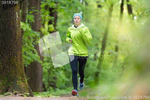 Image of Sporty young female runner in the forest. 