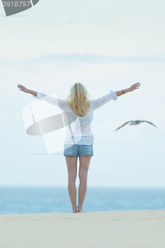 Image of Free woman enjoying freedom on beach at dusk.