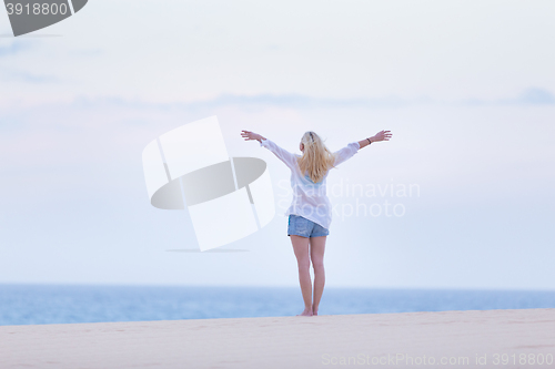 Image of Free woman enjoying freedom on beach in morning.