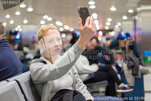 Image of Female traveler taking selfie on airport.