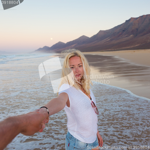 Image of Romantic couple holding hands on beach.