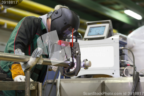 Image of Industrial worker setting orbital welding machine.