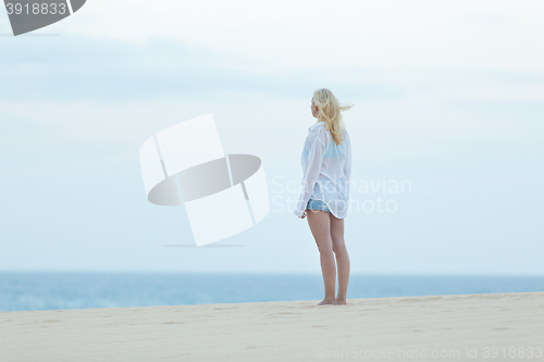 Image of Woman on sandy beach in white shirt.